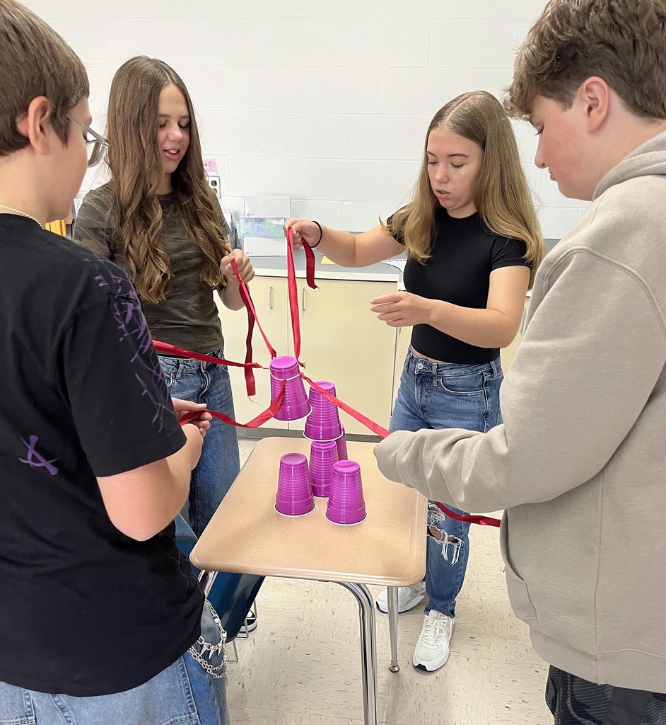 Four jr. high students work together on stacking several cups. 