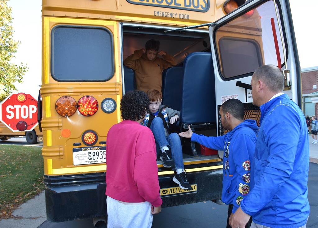 Two students and an administrator helping younger students evacuate a school. 