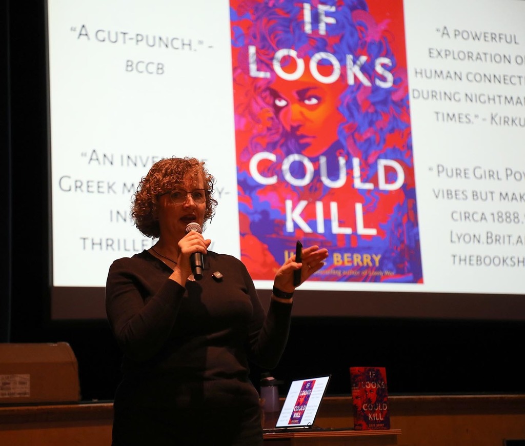 A female author standing in front of a screen in a school auditorium. 
