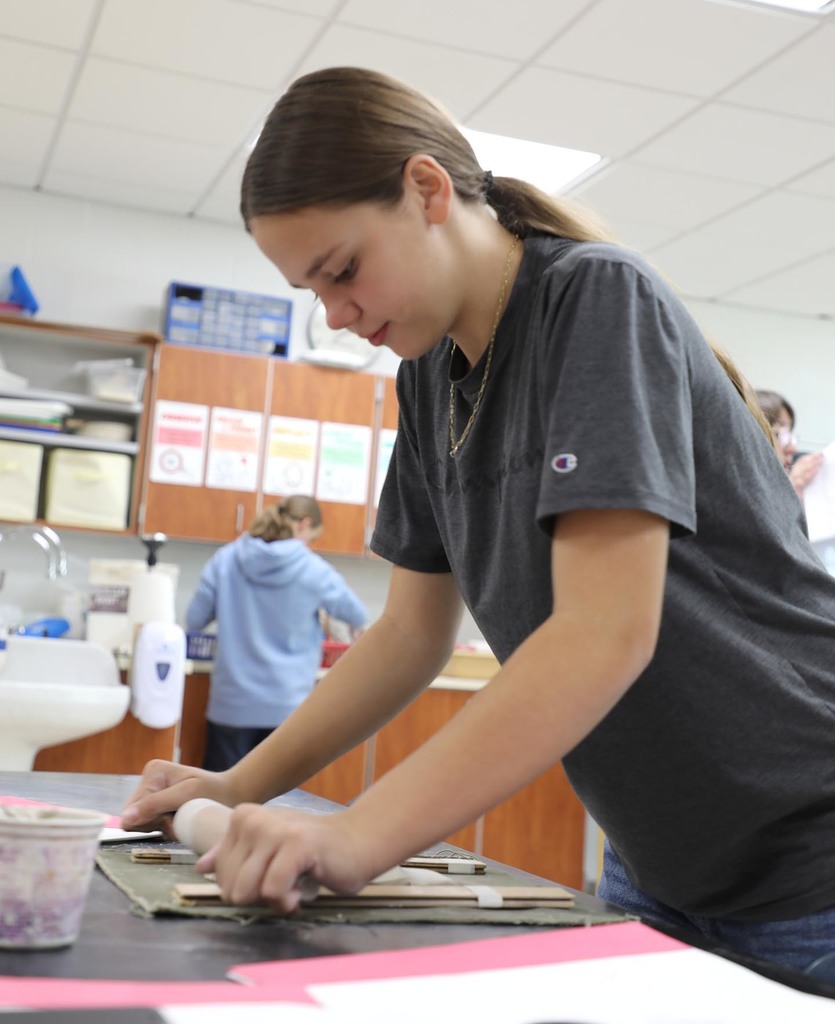 A female student working with clay in art class. 