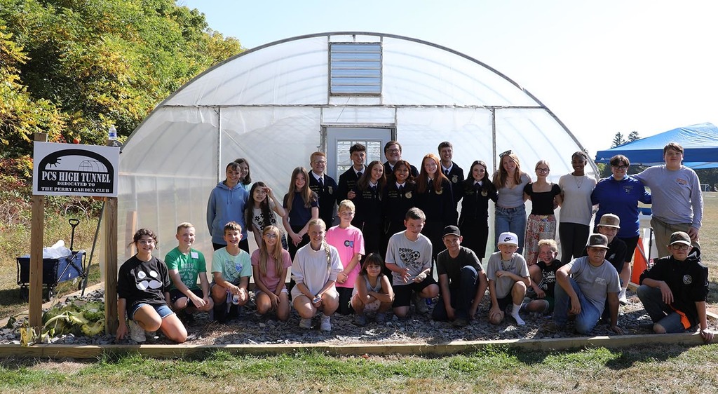 A group of students in front of a high tunnel.