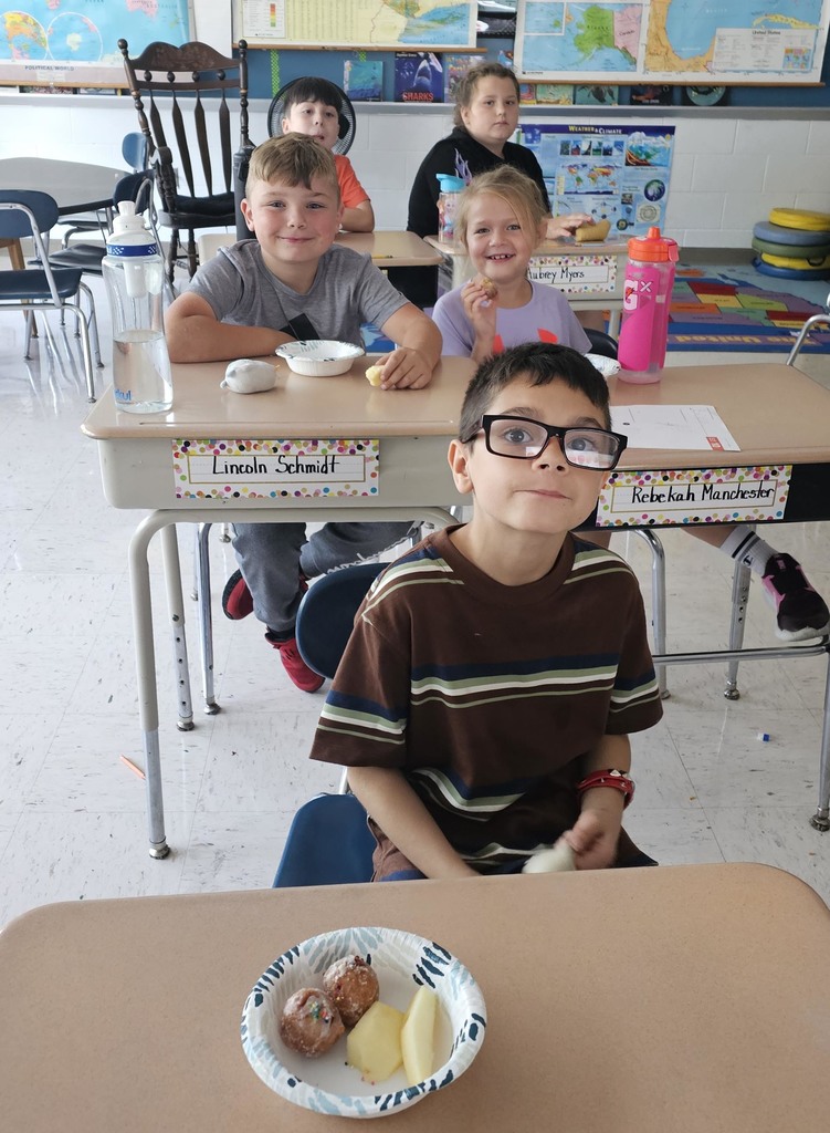 Elementary students eating applies and donuts.