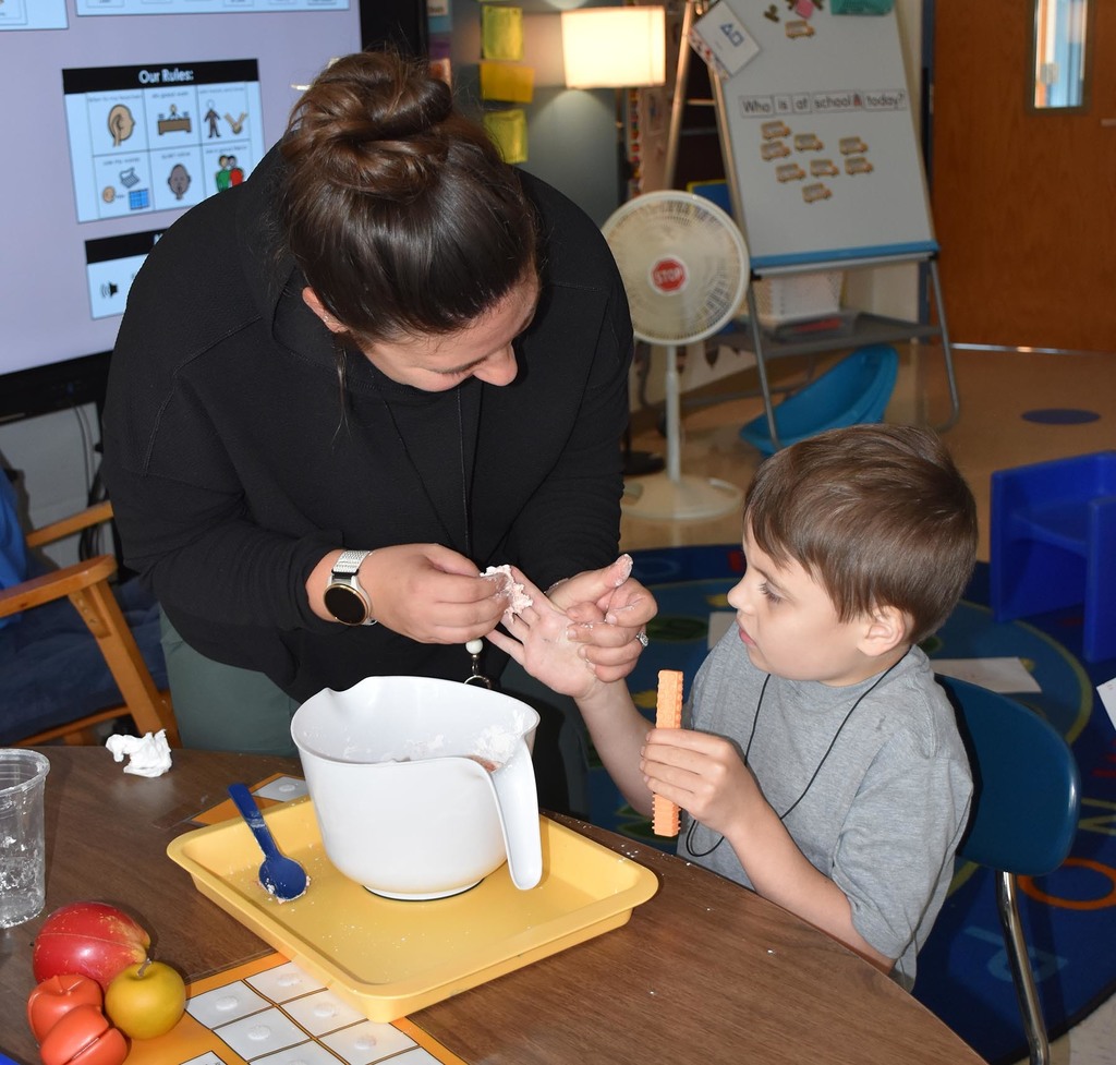 An adult woman putting something in the hand of an elementary student. 