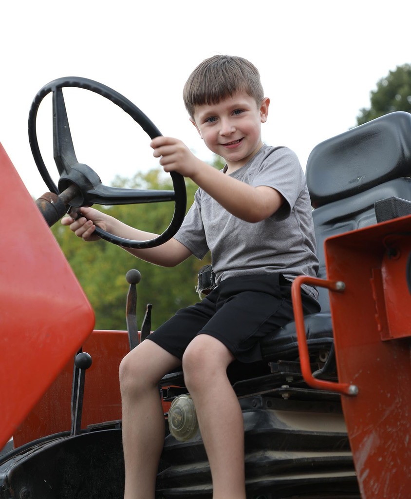 An elementary boy sitting on a tractor.