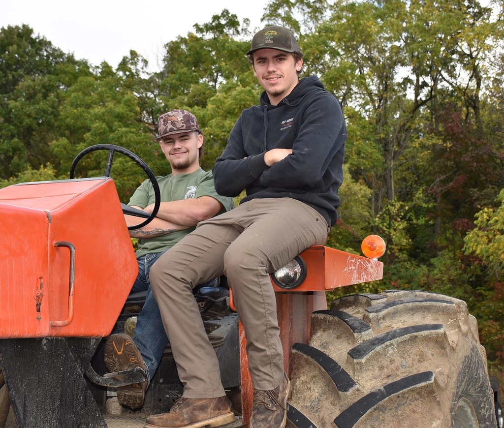 Two high school students on tractors. 