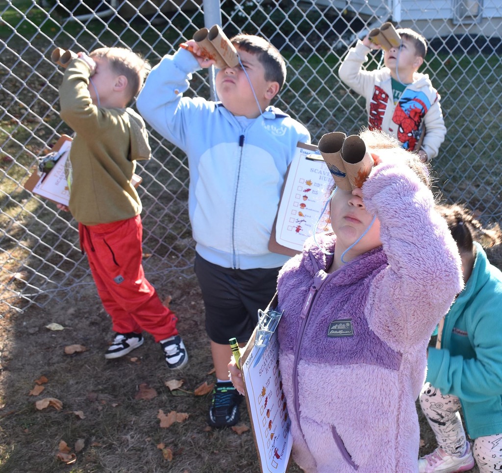 A group of elementary students looking toward the sky using homemade binoculars. 