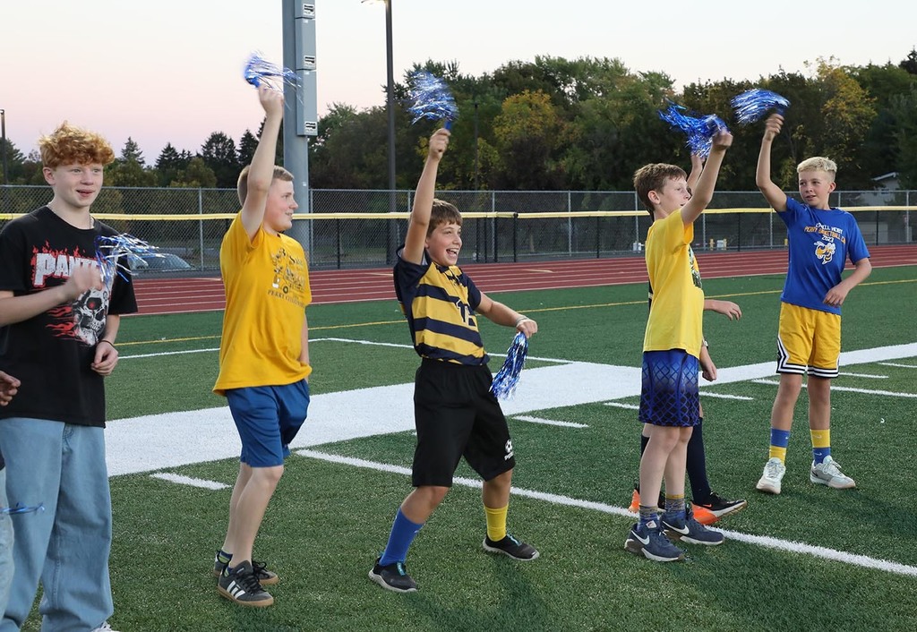 A group of Jr. High boys cheering on the sidelines of a football field. 