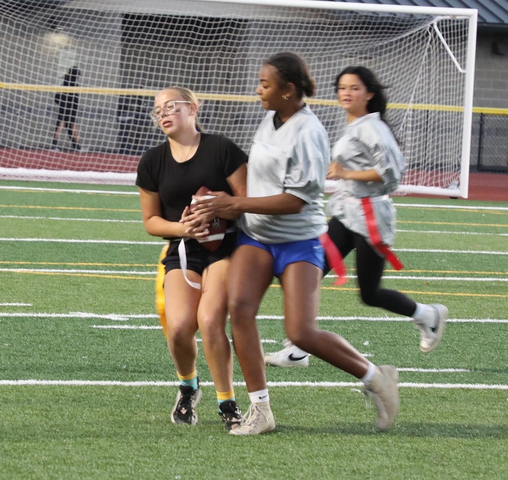 Two high school girls playing flag football. 