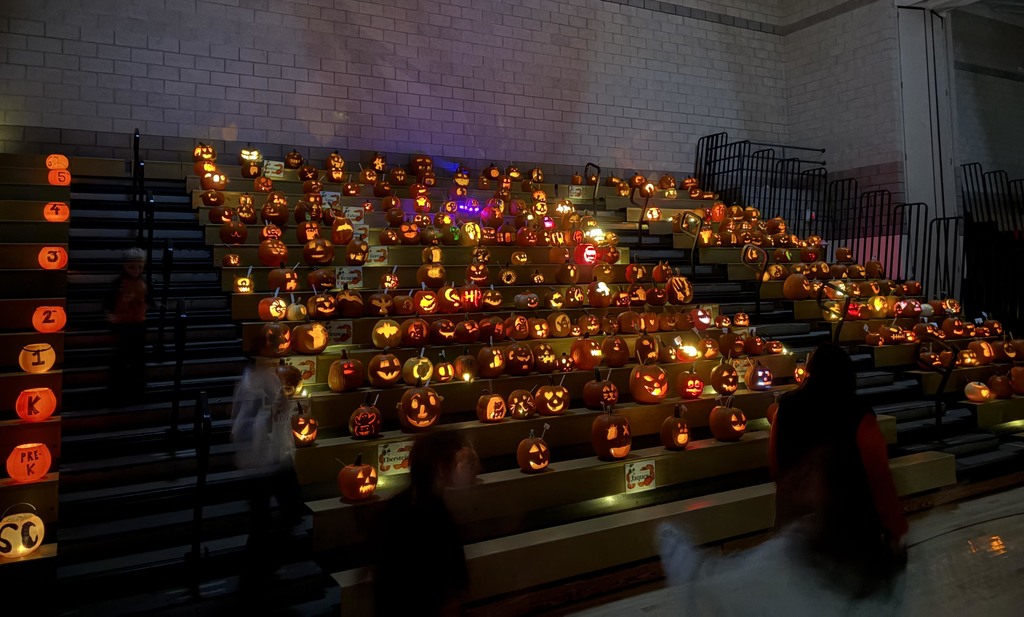 Dozens of pumpkin on the bleachers of a school gym. 