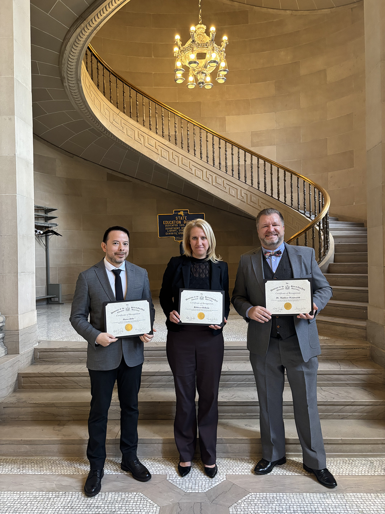 Two adult males standing with an adult female. They are all holding certificates. 