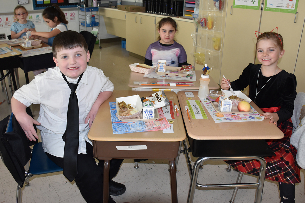 Three elementary students having lunch in their classroom. 