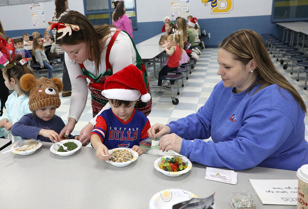 Several elementary students are helped by two adults in making "reindeer food." 