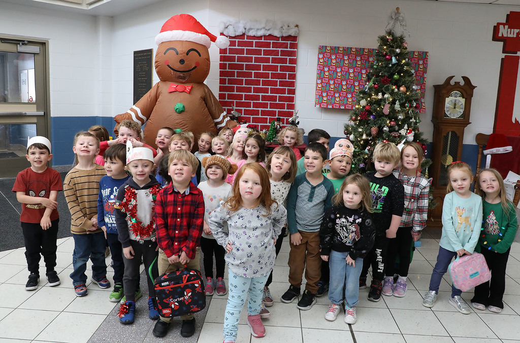 A group of elementary students posing with a gingerbread man. 
