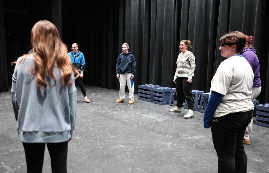 Several people standing in a circle on an auditorium stage. 
