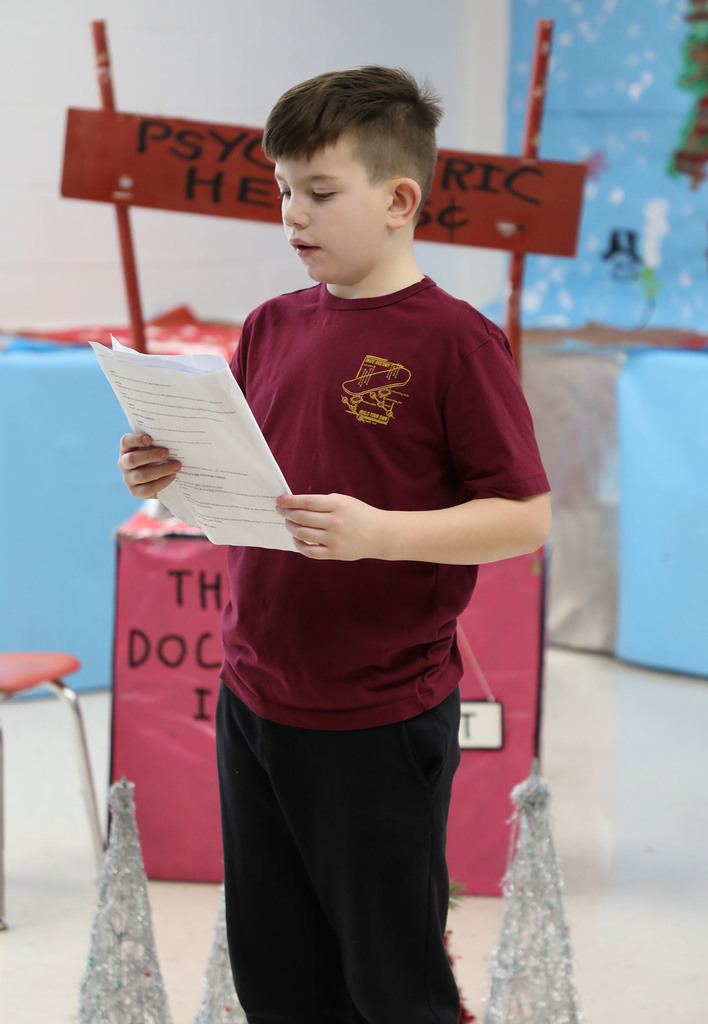 An elementary boy reading from a script. 