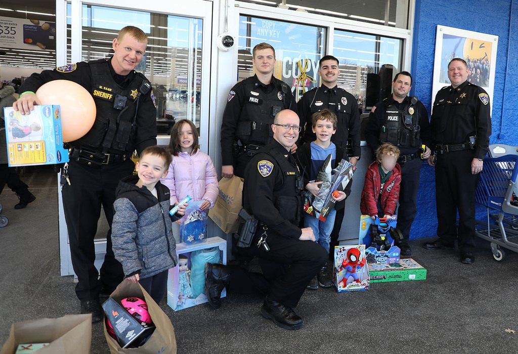 A group of children standing with law enforcement officers. 