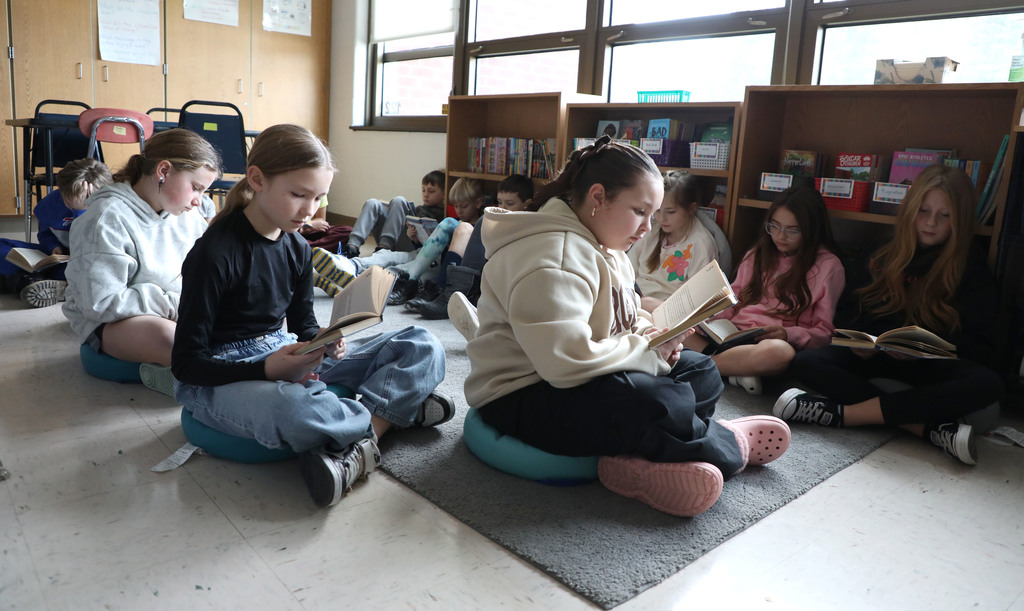 A group of fourth graders reading a book. 