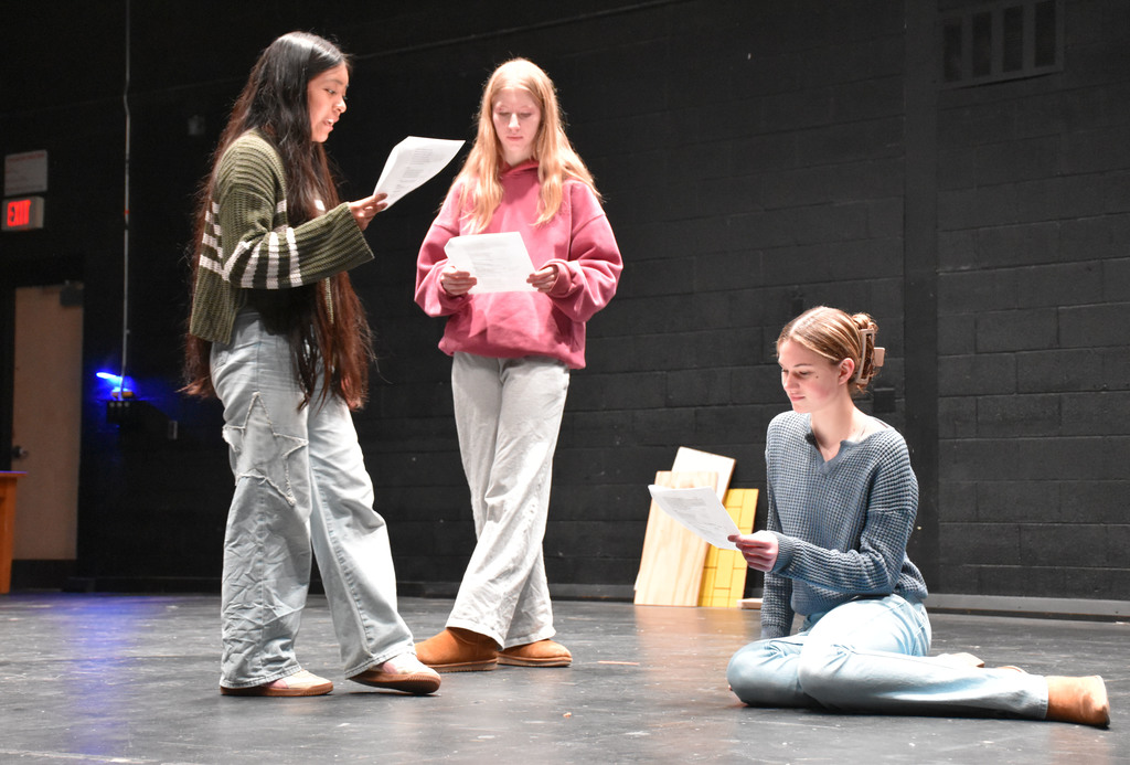 Three high school females on a performing arts stage. 
