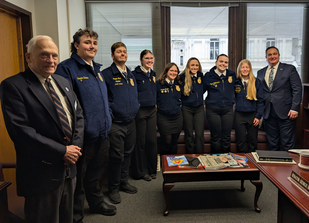 A group of high school FFA members posing for a photo with two adult males. 