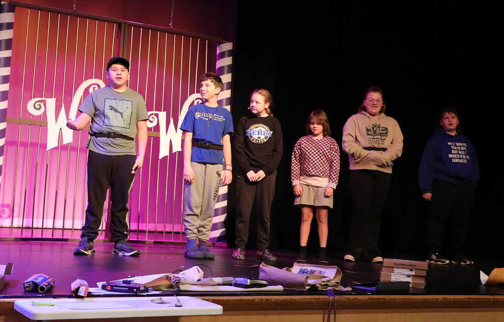 A group of students standing on an auditorium stage. 