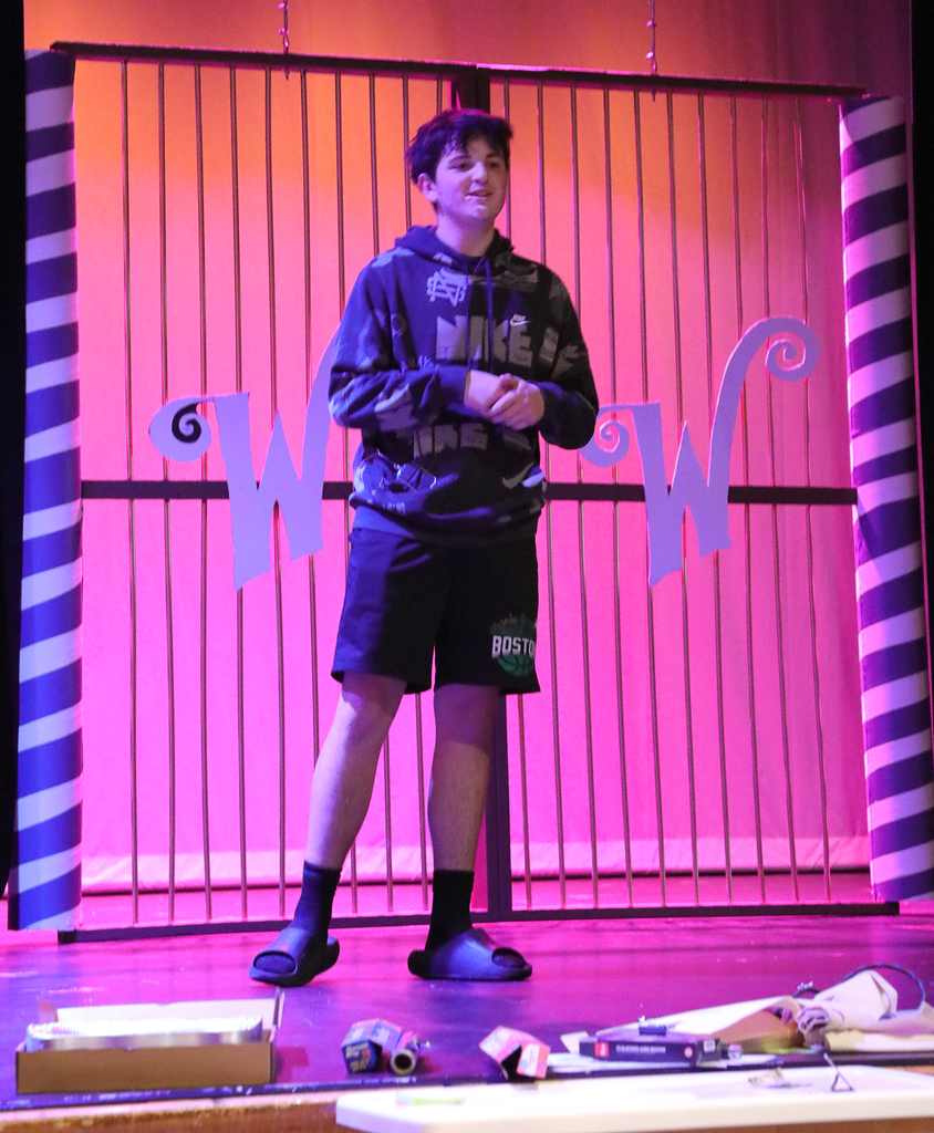 A teenage boy standing on a high school stage. 
