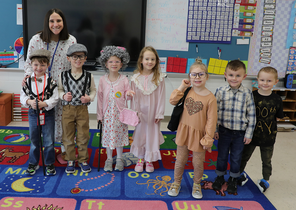 A group of kindergartners and their teacher posing. 