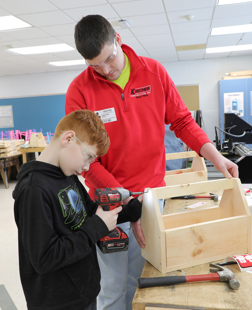 An adult male helping a 5th grade boy build a toolbox. 