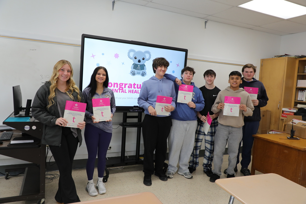 A group of high school students standing in  classroom. 