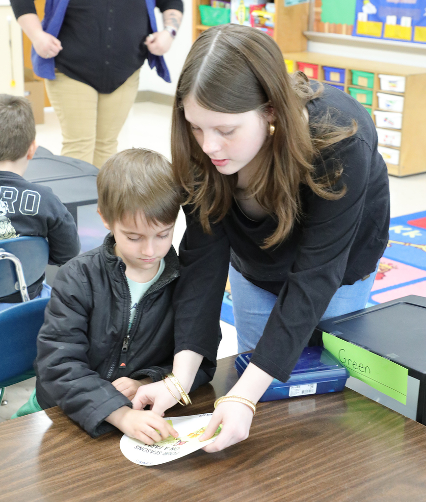 A jr. high student helping a kindergartner with a project. 