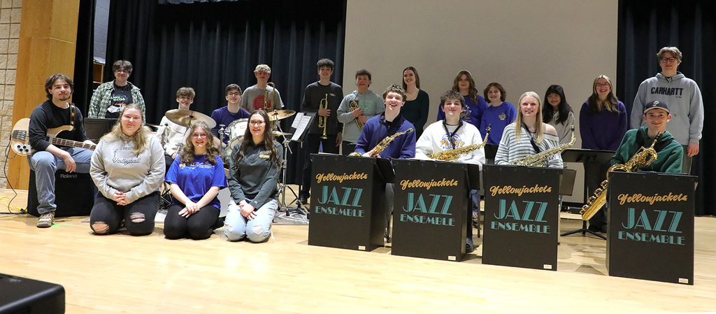 A group of high school students on a stage. Some have musical instruments. 