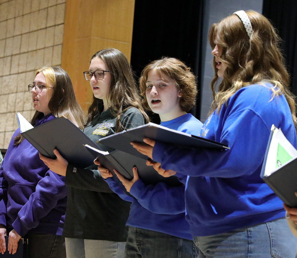 Four high school students holding notebooks. 
