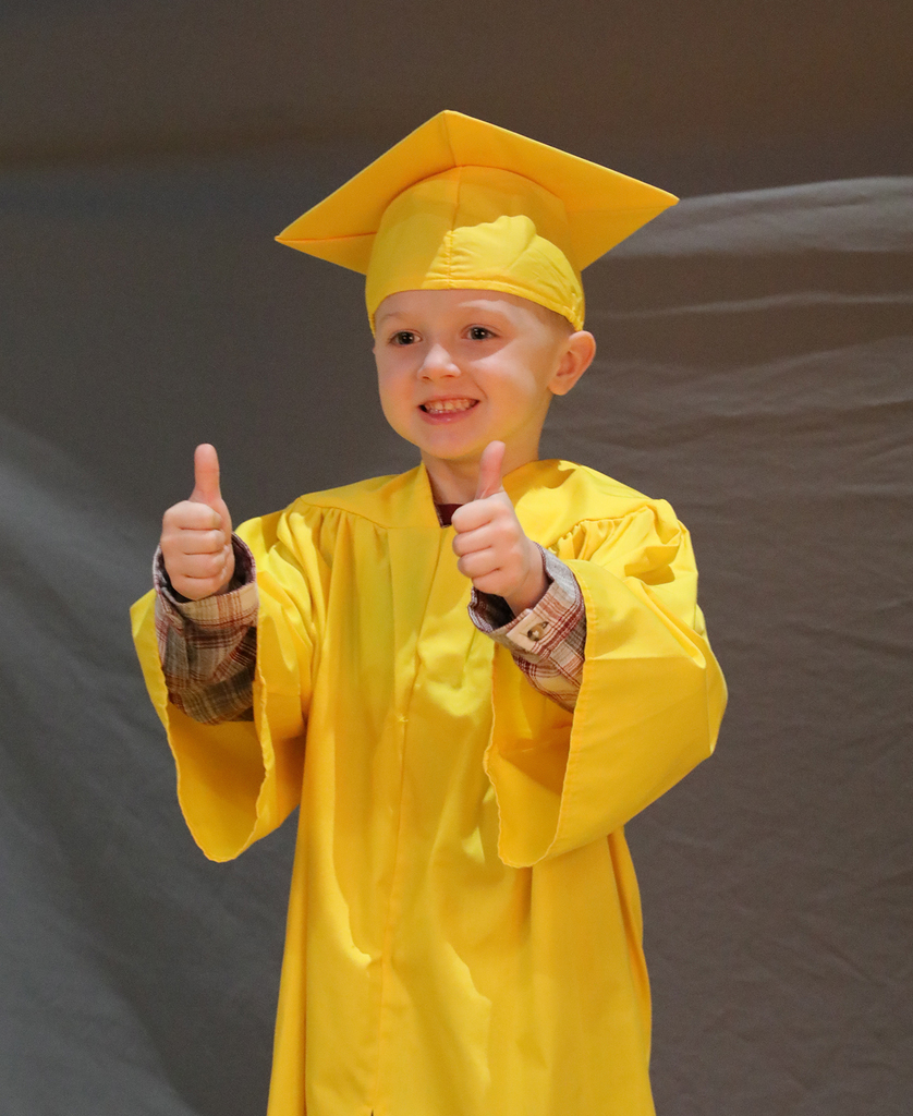 A UPK graduate holding up two thumbs up while posing for a photo. 