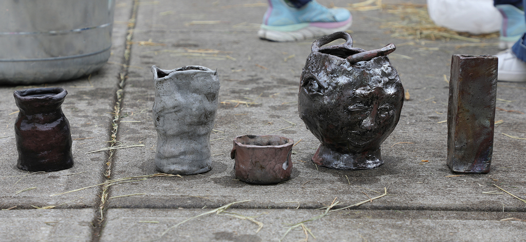 Five pieces of pottery sitting on the ground. 