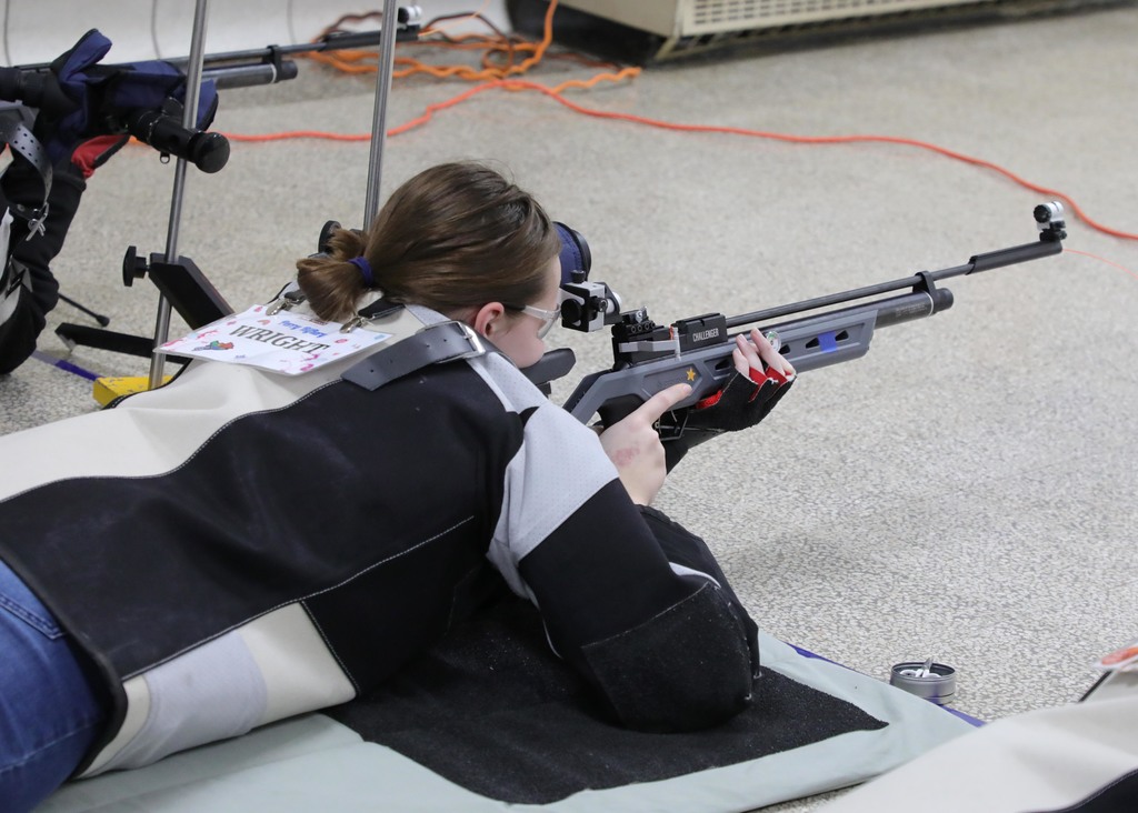 A high school female competing in a riflery competition. 