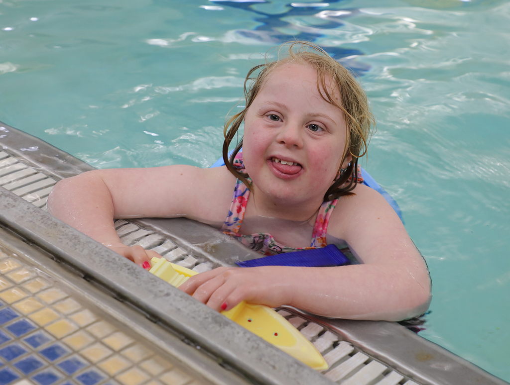 A smiling child in a school swimming pool. 