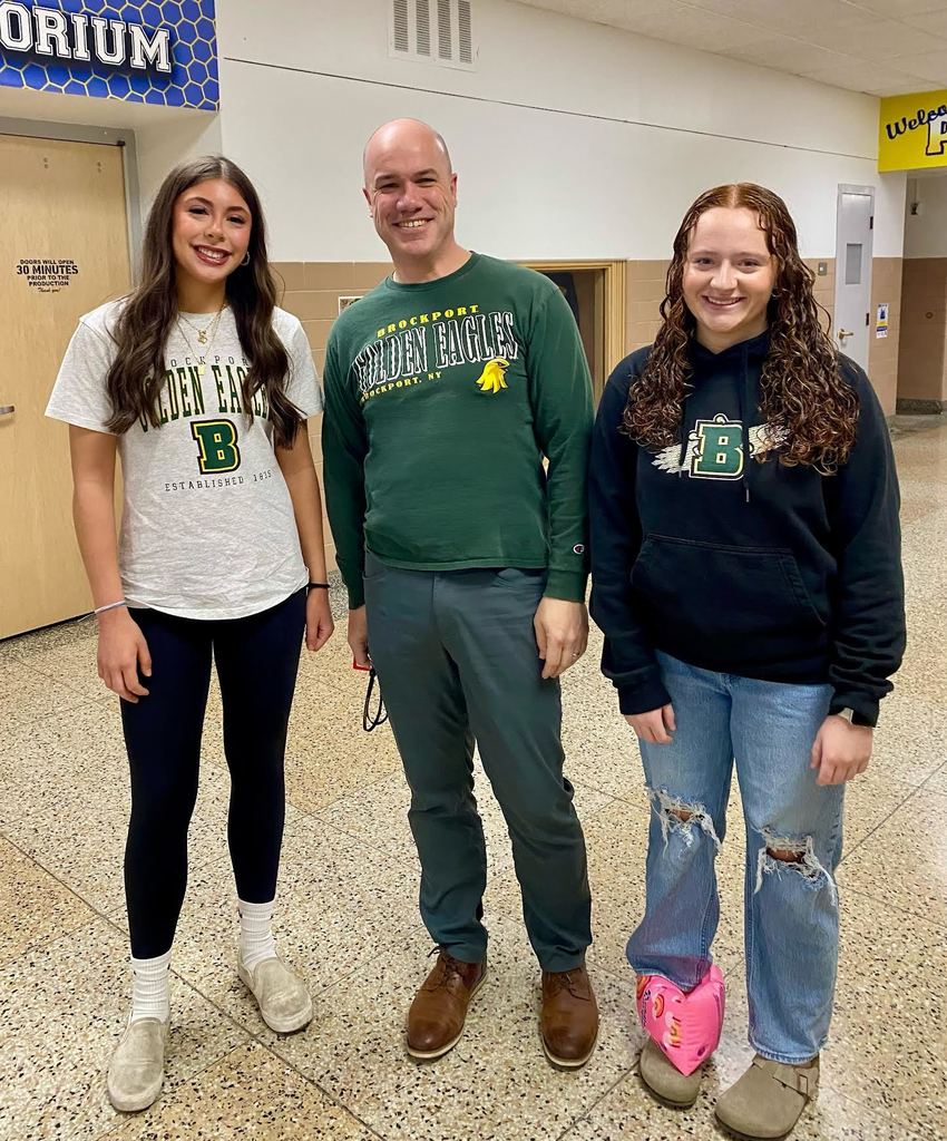 An adult male standing with two high school seniors. 