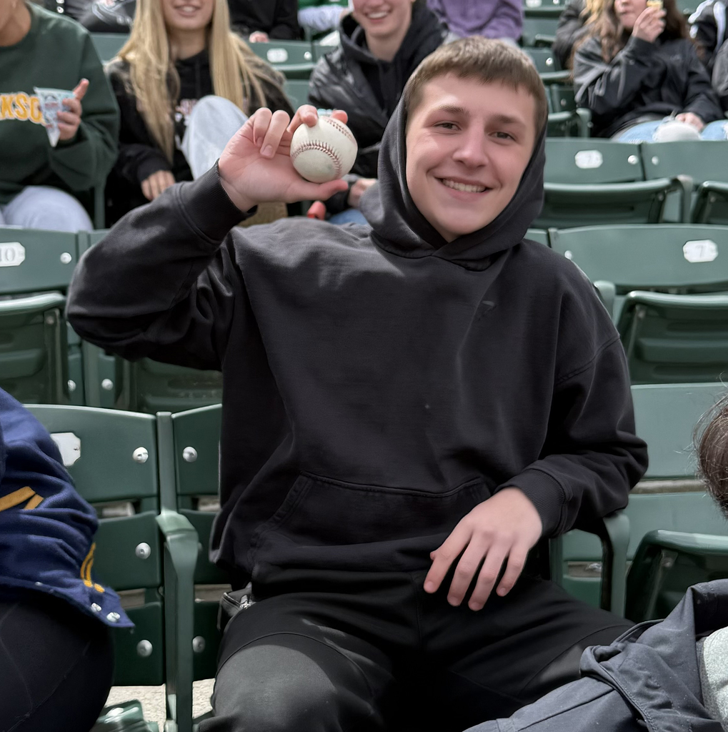 A high school boy holding up a baseball. 