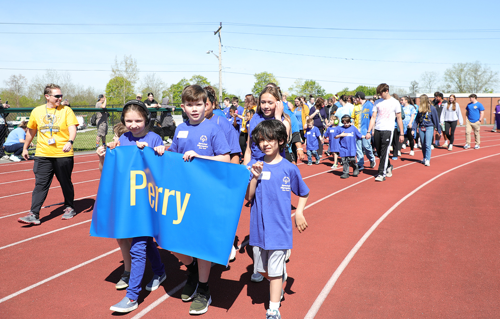 A group of students and adults walking in a parade. 
