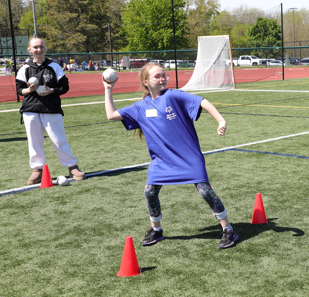 An elementary student throwing a softball as another student looks on. 