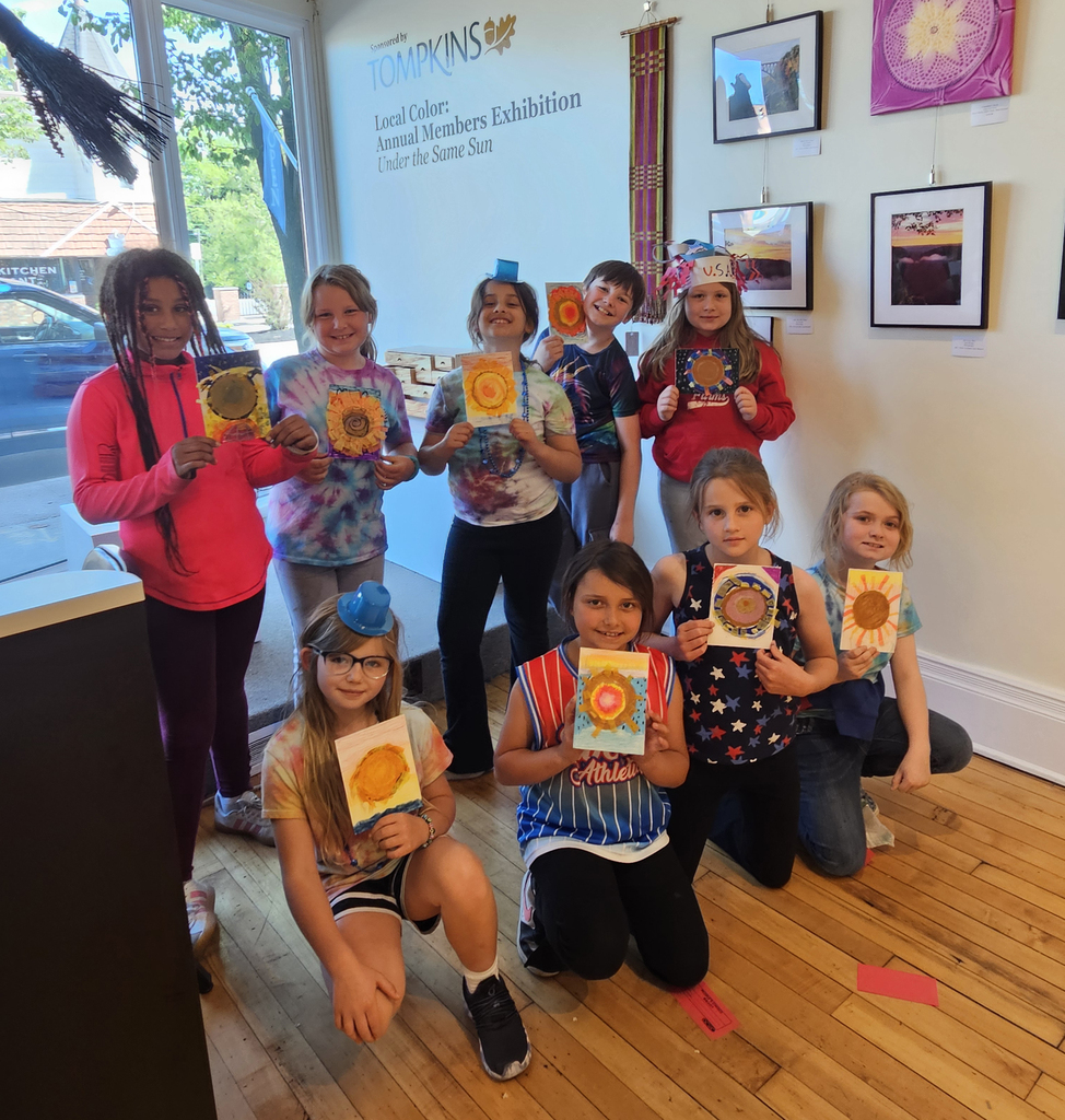 A group of elementary students holding artwork. 