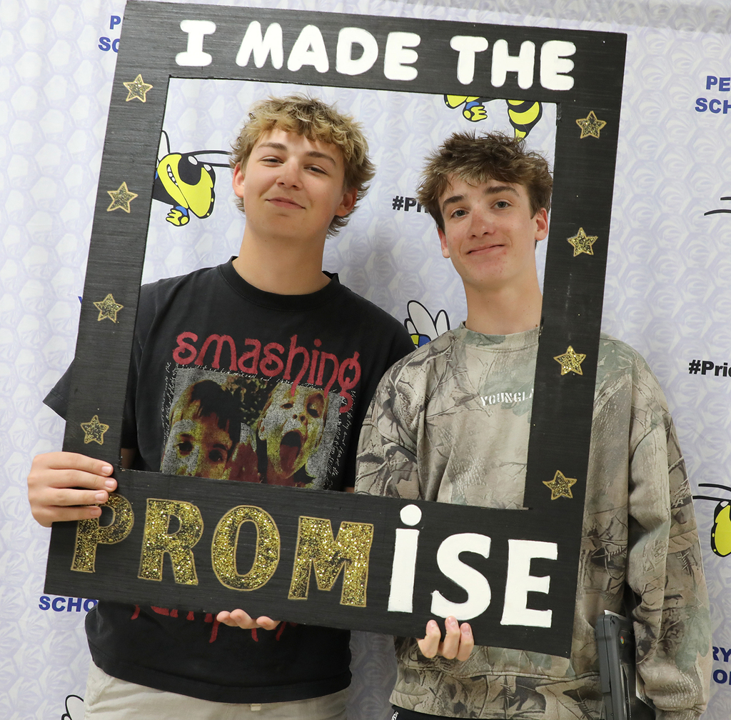 Two high school boys posing with a sign. 