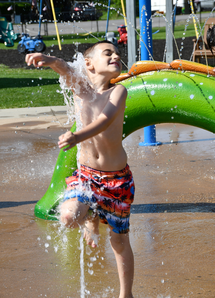 A boy playing in a splash pad. 