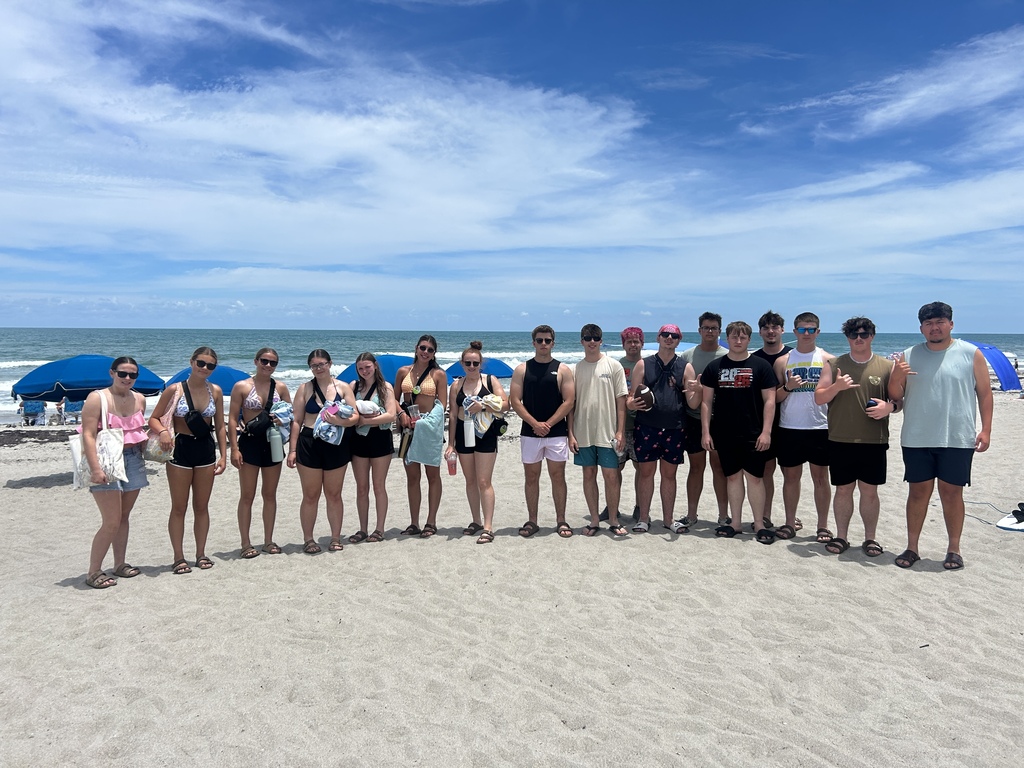 A group of teenagers standing on a beach. 