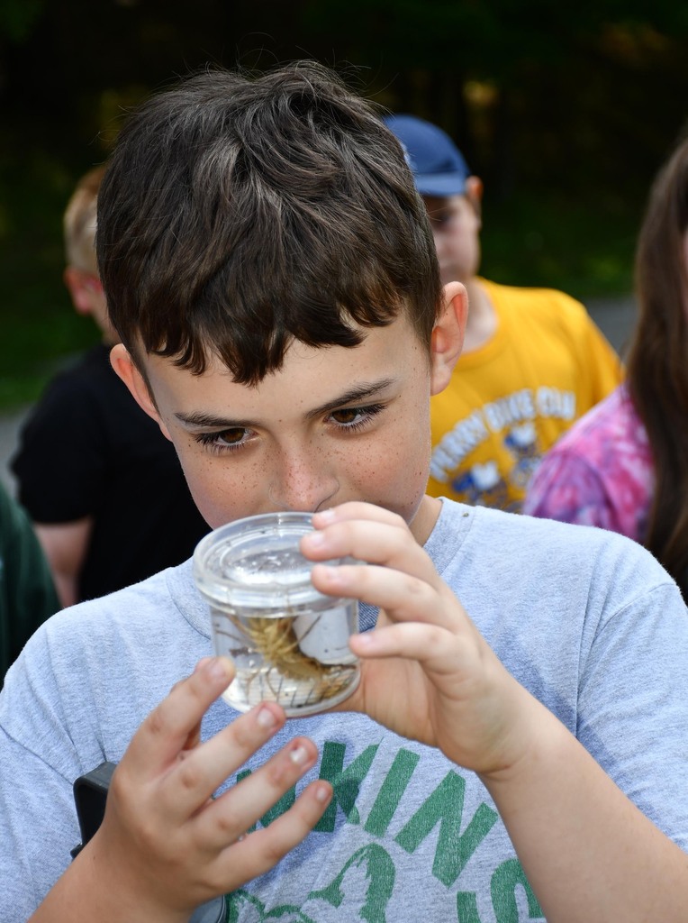 A boy holding a jar with something in it. 