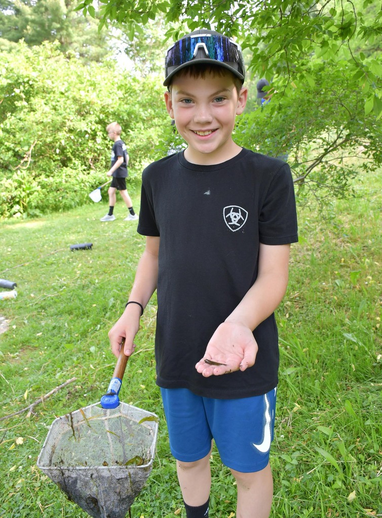 A boy holding a net and a small fish. 