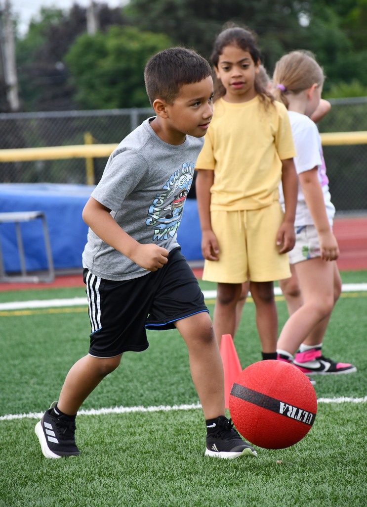 A boy dribbling a ball with his feet. 