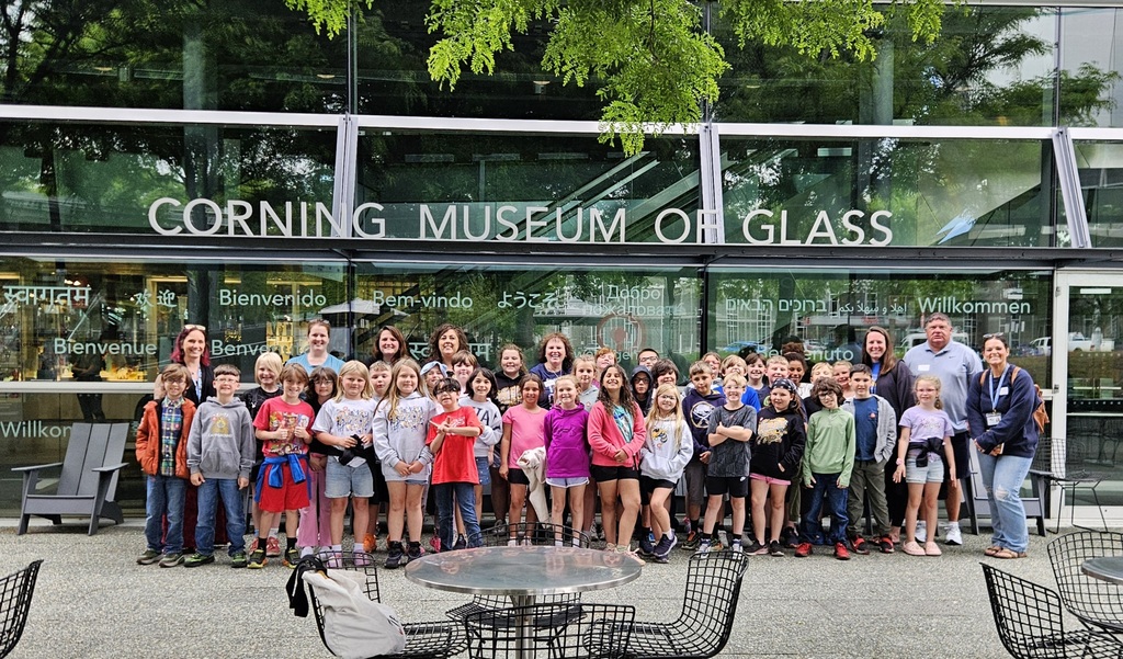 A group of students and adults in front of the Corning Museum of Glass. 