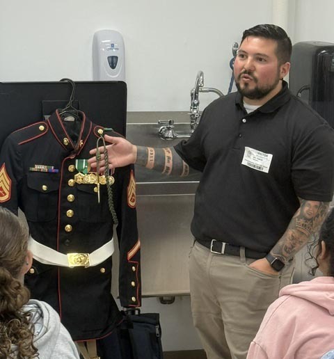 A man standing in front of a Marine Corps uniform. 