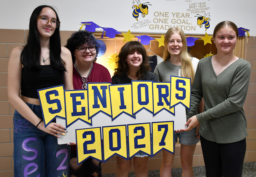 Five seniors holding a sign "Seniors 2027." 