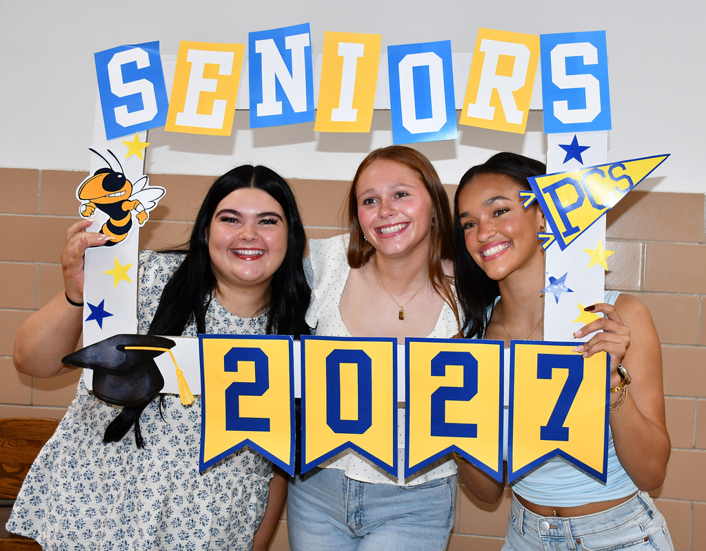 Three girls hold a "Senior 2027" sign. 